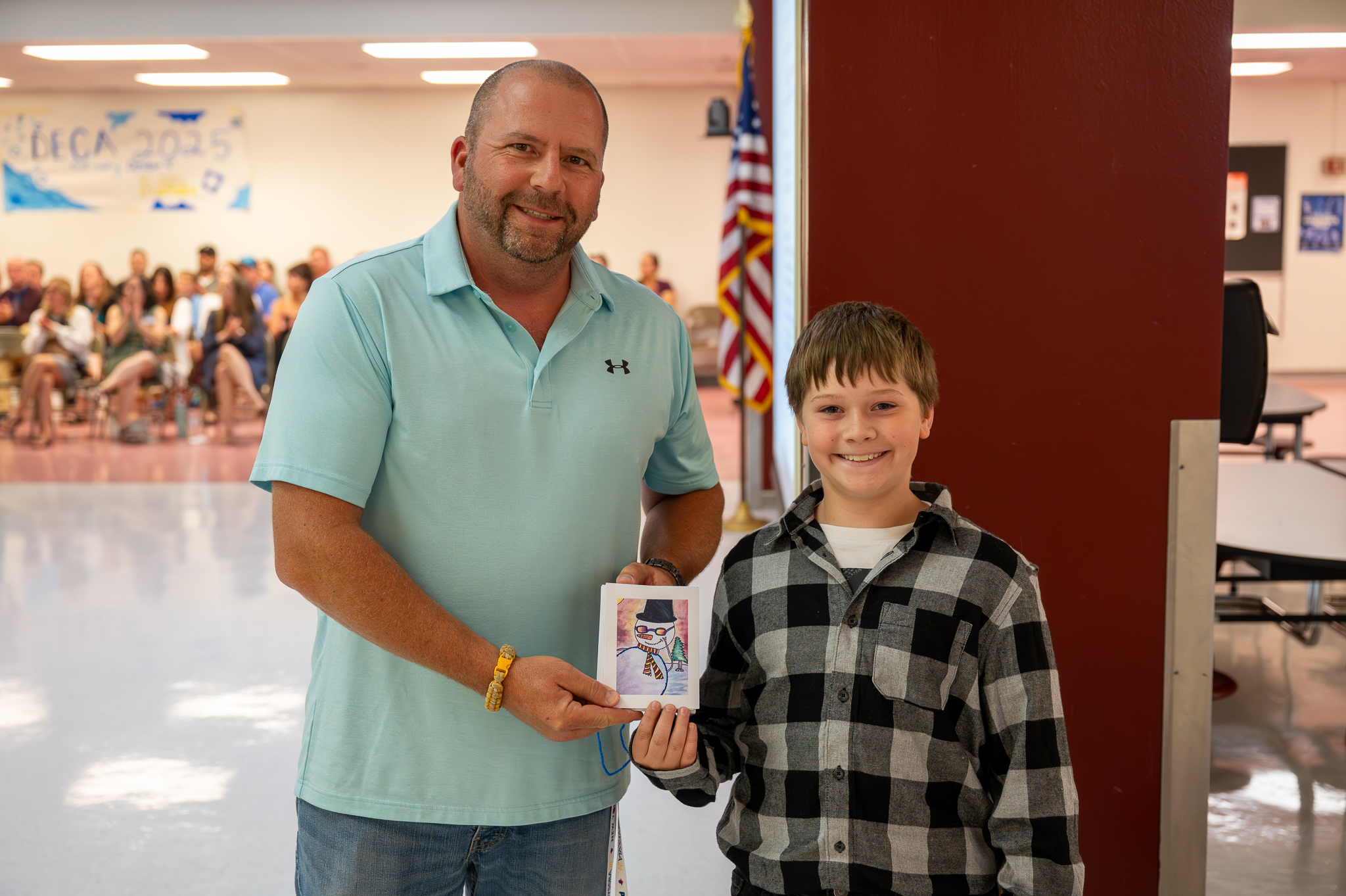A board of education member standing proudly with a student, who gifted them artwork.